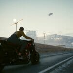 V rides a motorcycle through Night City in Cyberpunk 2077