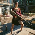 V poses in Night City with her sniper rifle in Cyberpunk 2077